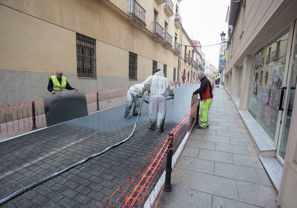 Varios operarios trabajan en echar la última capa de pintura sobre el pavimento de cemento impreso en la calle Parras.