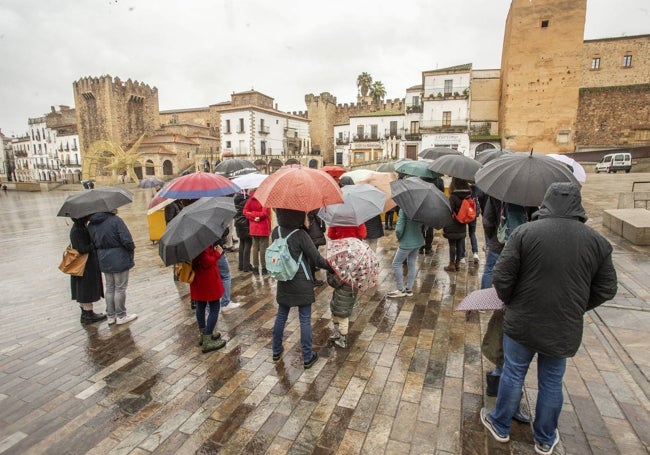 Turistas en la Plaza Mayor de Cáceres en un día de lluvia.