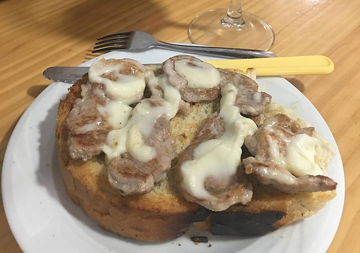 Imagen principal - Tosta de solomillo con torta, aperitivo de queso por cortesía de la casa y pizarra con las raciones.