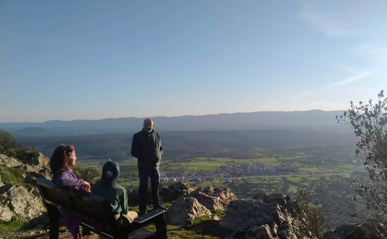 Personas disfrutando del paisaje de La Siberia desde el banco instalado en la sierra de Mirabueno de Garbayuela.