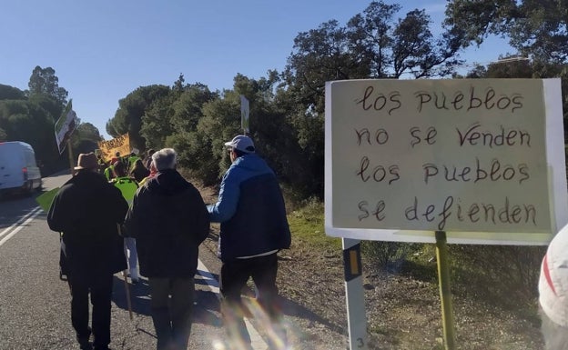 Imagen principal - Mensajes contra el proyecto minero en la imagen superior. Abajo, algunos manifestantes con sus pancartas por la carretera y vehículos que han hecho el recorrido desde Holguera. 