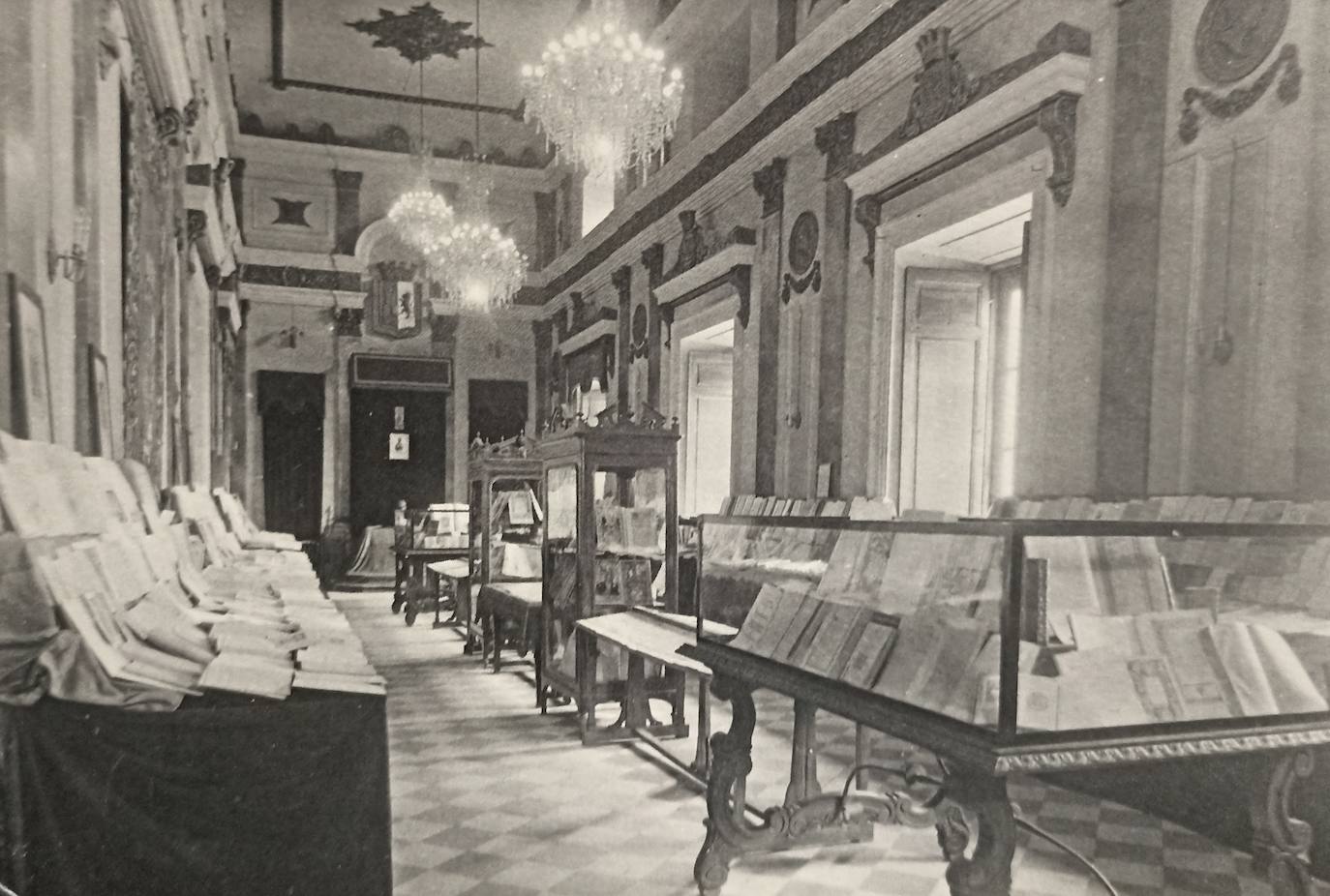 Salón de Plenos del Ayuntamiento de Cáceres en 1948 con una exposición de libro antiguo. En el techo las lamparas de Alfonso XII.