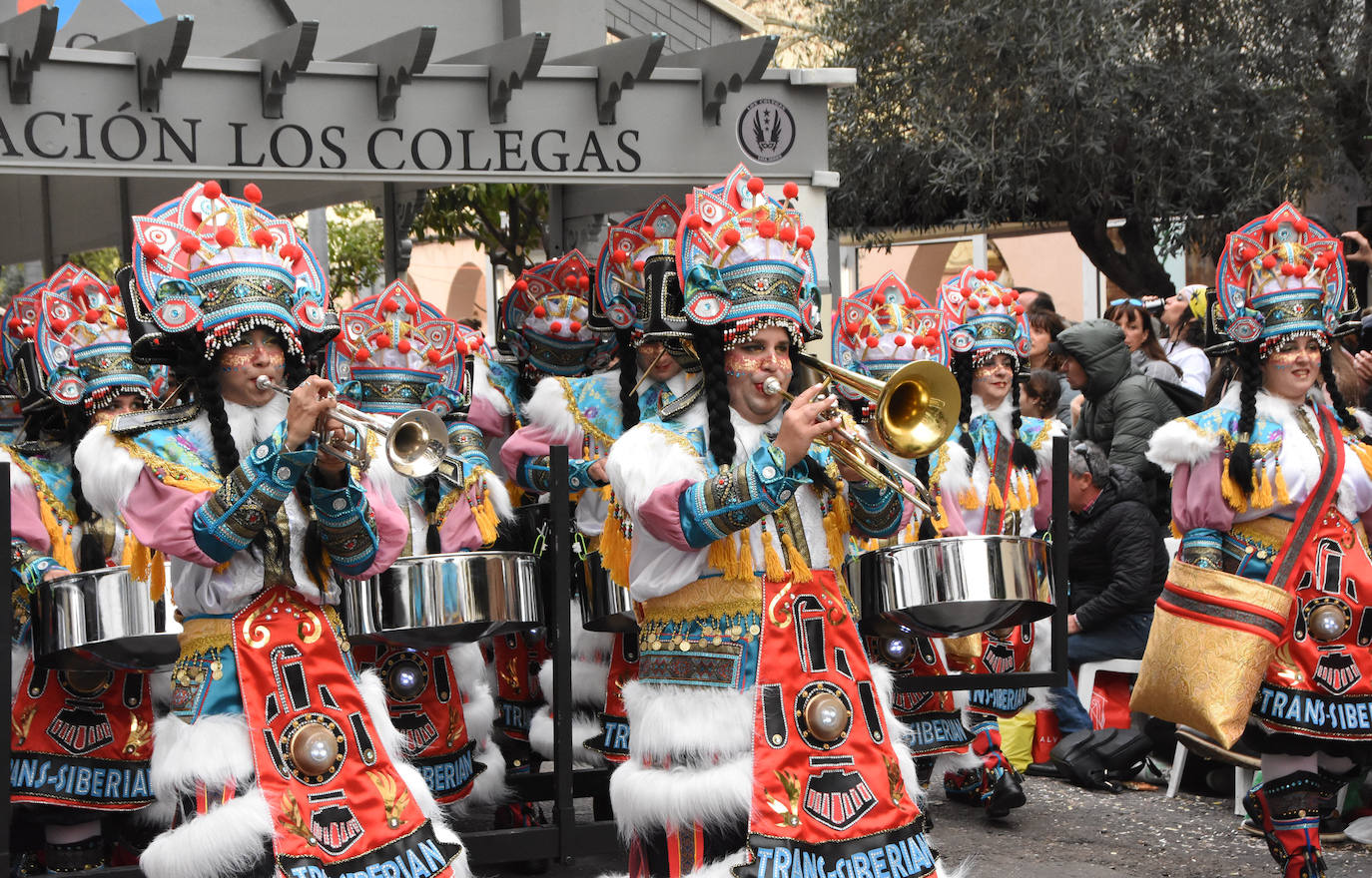 Los Colegas, la única comparsa cacereña, volvió al desfile tres años después viajando en el tren transiberiano, el que une Moscú con China. La última vez que este grupo fue en medio de transporte, en el Titanic, ganaron. Están precedidos por un enorme tren en el que entran todos sus bailarines y, tras el cuerpo de baile, los músicos van en una impresionante estación. El traje de Los Colegas no desmerece al montaje que les acompaña. Incluye elementos rusos y chinos e incluso la luz del tren. Han sido ovacionados por el público. 