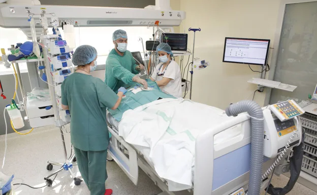 Tres sanitarios interviniendo a un paciente en la UCI del Hospital Universitario de Cáceres, con el ordenador a la derecha que registra todos sus parámetros. /Armando méndez