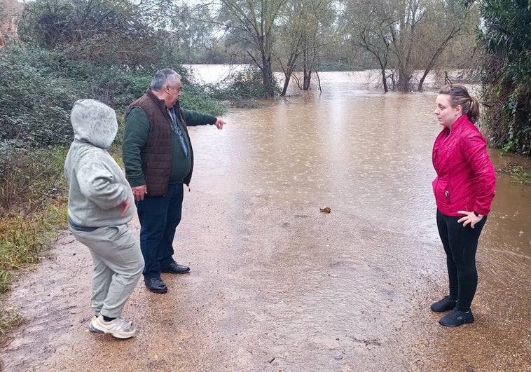 Antonio Vadillo junto a su nuera y su nieto esta mañana señalando donde acaba de colocar una piedra como marca para ir confirmando la crecida del río Gévora.