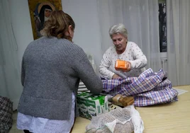 María del Carmen Ruiz, voluntaria de Cáritas, ayuda a llenar su carro a una usuaria.