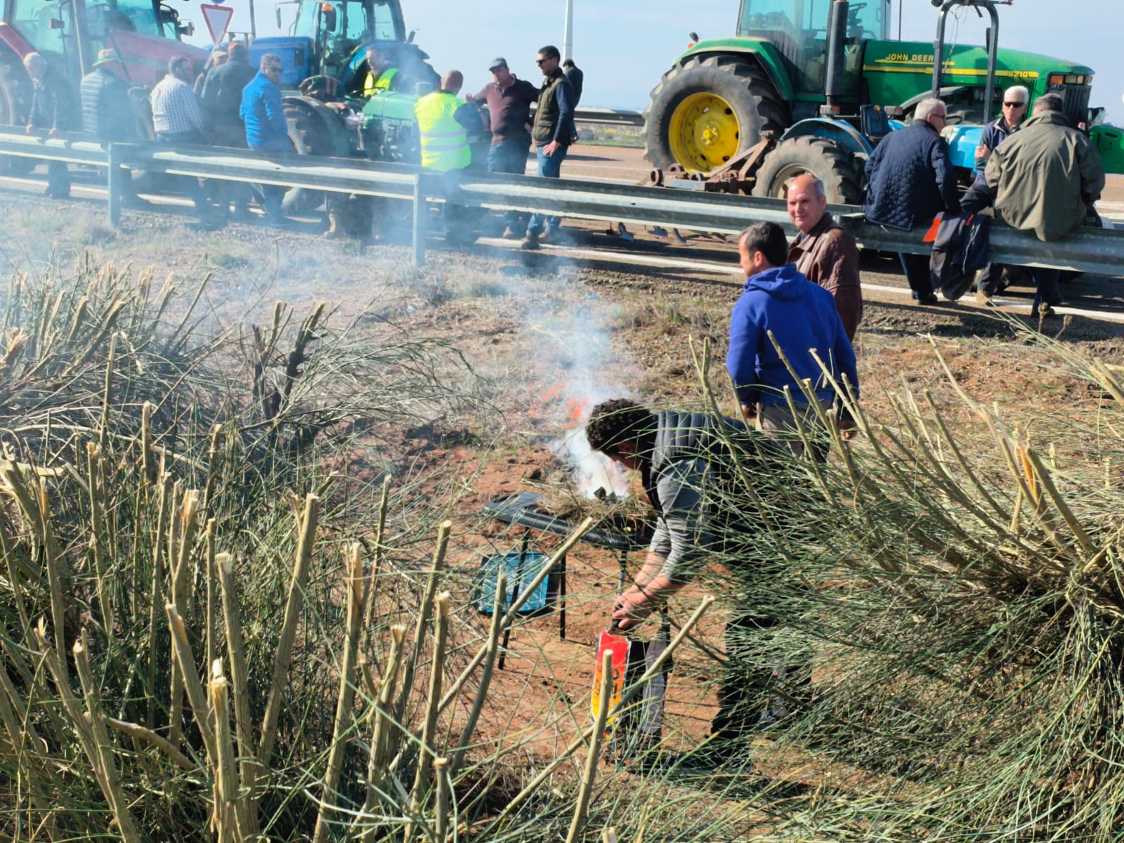 Manifestantes se disponen a encender una barbacoa junto a la A-66 para hacer algo de comer.