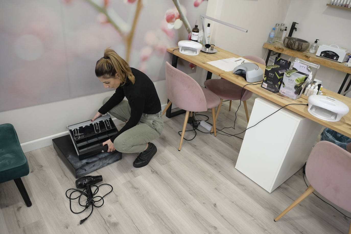 Una de las trabajadoras del centro de estética  Victoria Durán enseña la caja registradora, que reventó durante el robo, y con la que golpearon el suelo de madera.