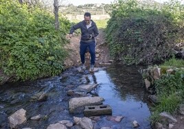 Un hombre cruza entre las piedras la Ribera. Se reclama un puente de madera.