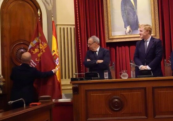 El alcalde, Ignacio Gragera, y el secretario del Ayuntamiento miran la colocación de la bandera en el salón de plenos el día de su aprobación en octubre de 2023.