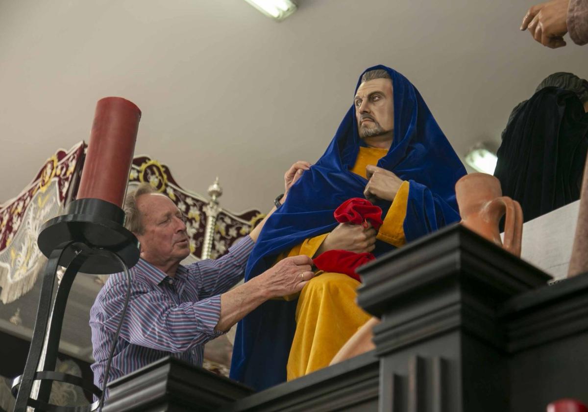 Un hermano de la cofradía de la Argentina prepara el paso de la Sagrada Cena.