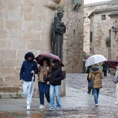 Un grupo de turistas con paraguas en la plaza de Santa María de Cáceres este miércoles.
