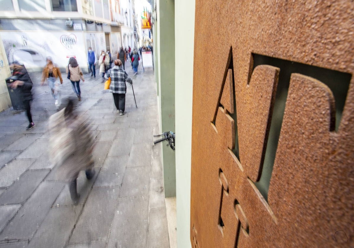 En primer plano, placa de apartamentos turísticos situada en un edificio de la calle Pintores.