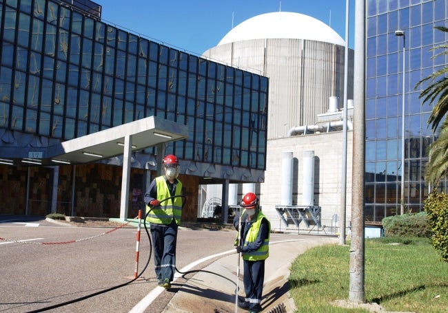 Dos operarios trabajando en la central, con uno de los reactores detrás.