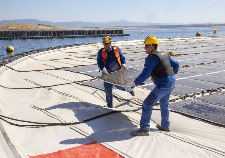 Dos operarios reponen un módulo solar en la planta fotovoltaica flotante ubicada sobre la presa de Sierra Brava.