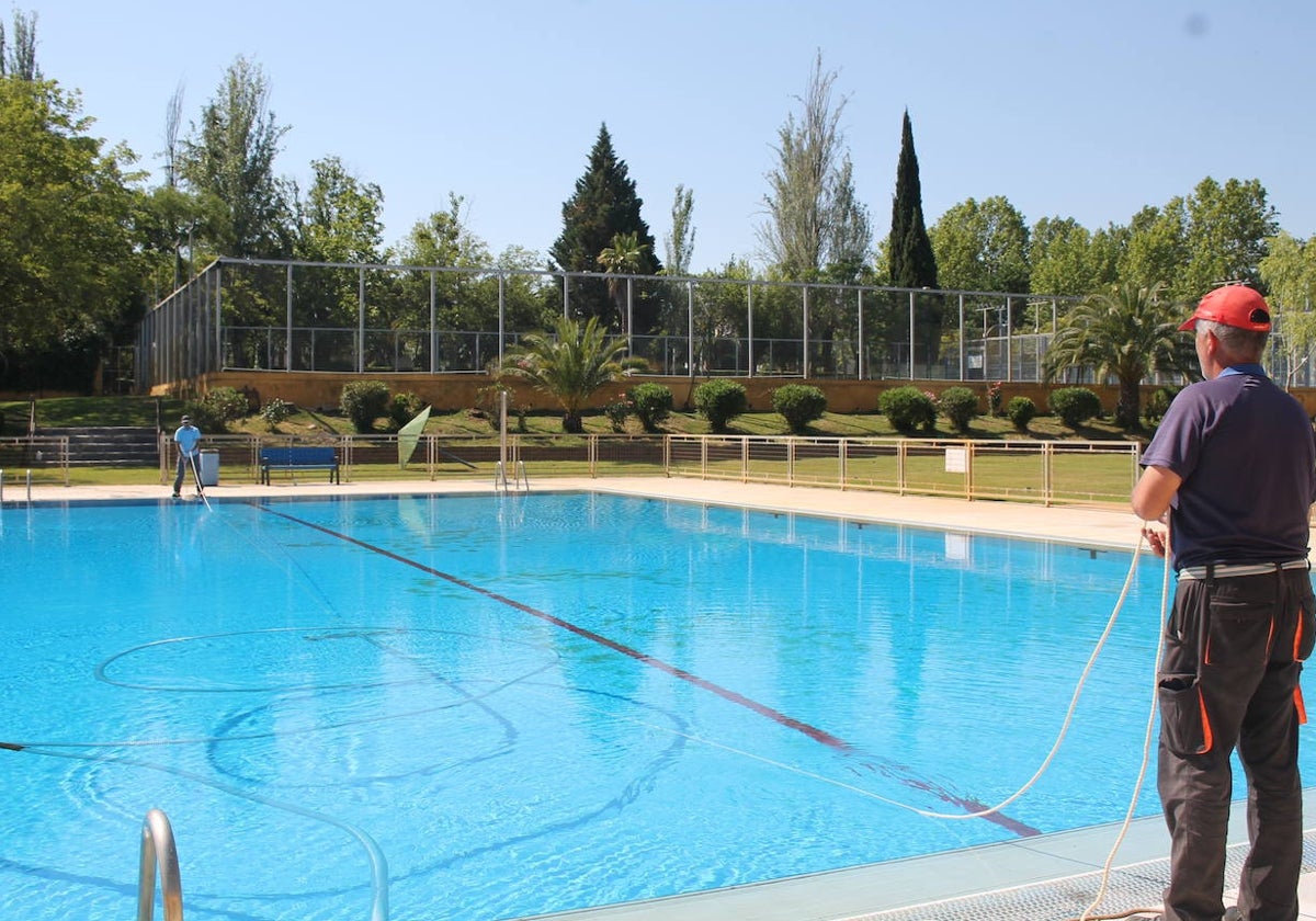 Dos operarios del Ayuntamiento de Monesterio, ayer, con el barrefondos en la puesta a punto de la piscina municipal de la localidad.