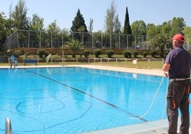 Dos operarios del Ayuntamiento de Monesterio, ayer, con el barrefondos en la puesta a punto de la piscina municipal de la localidad.