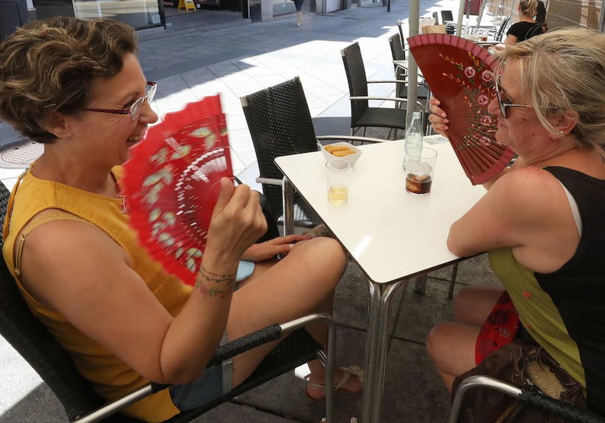 Dos mujeres abanicándose en una terraza.