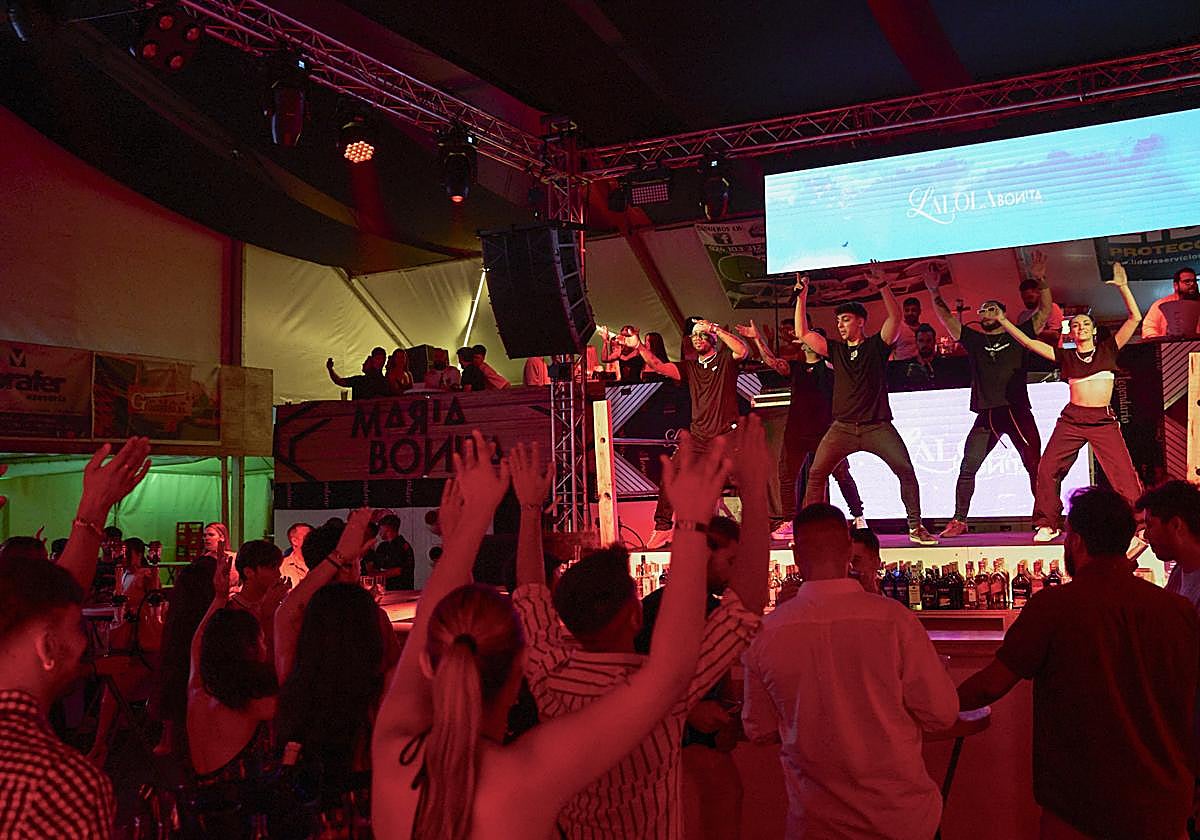 El público baila al compás de los animadores en una de las casetas de la feria.