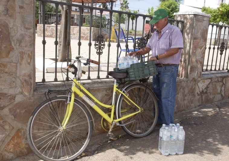 José González carga botellas de agua en su bicicleta el pasado miércoles en la plaza del Emigrante de Guadajira.