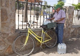 José González carga botellas de agua en su bicicleta el pasado miércoles en la plaza del Emigrante de Guadajira.