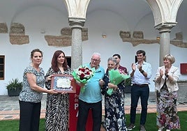 El homanejado, junto a su mujer, durante la entrega de placas y ramos de flores.