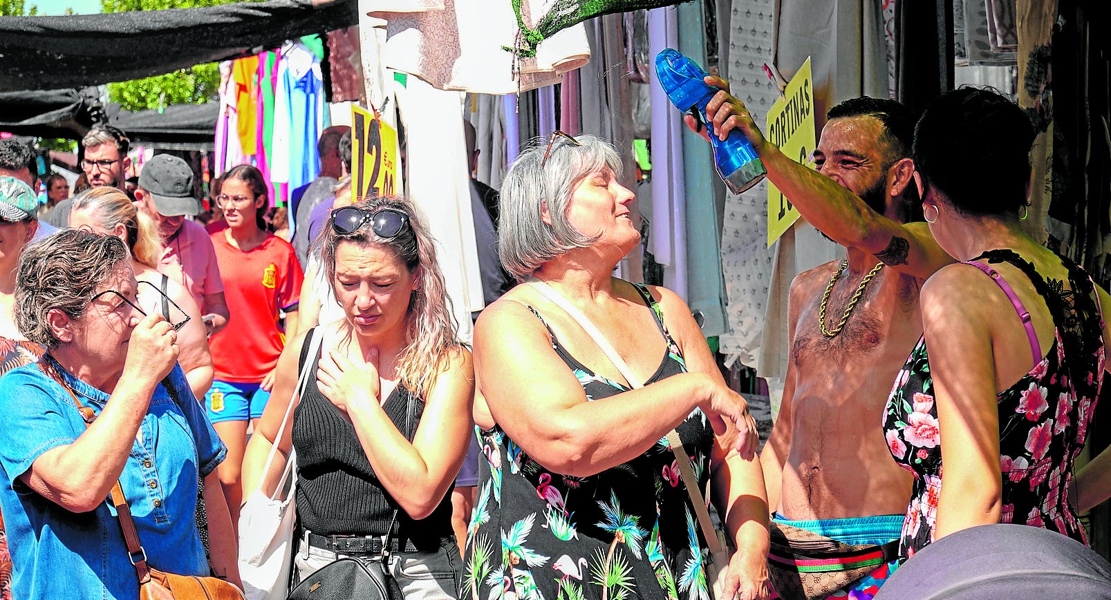Los vendedores refrescan a los clientes con agua y ventiladores de mano para ayudarles a comprar con calor.