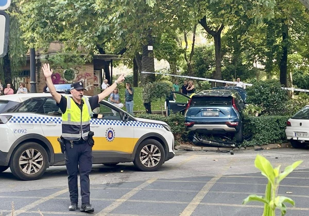 Un agente regula el tráfico con la zona acordonada y el coche siniestrado al fondo.