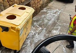 Operario municipal limpiando un punto de recogida de basura.