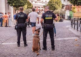 Dos agentes junto al perro de la Policía Local, este jueves, en la calle Santa Julia, frente a la plaza de España.