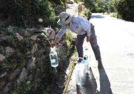 Un vecino de Barrado llena sus garrafas en una fuente de la localidad.