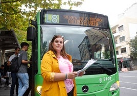 Victoria Campos, con una de las hojas de recogida de firmas, delante de un bus de la línea 8.