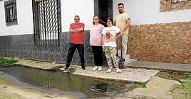 Soledad Jiménez junto a sus vecinos en la puerta de su casa, donde no deja de salir agua sucia del colector.