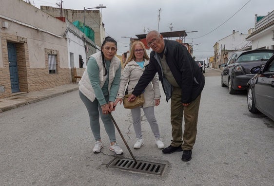 Yolanda y Milagros González y Fernando Parra con una de las alcantarillas que abrieron el viernes.