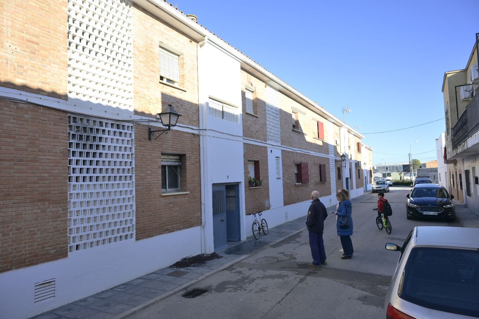Varios vecinos de la calle Juan XXIII de Talavera la Real observan la vivienda que ha sufrido el incendio.