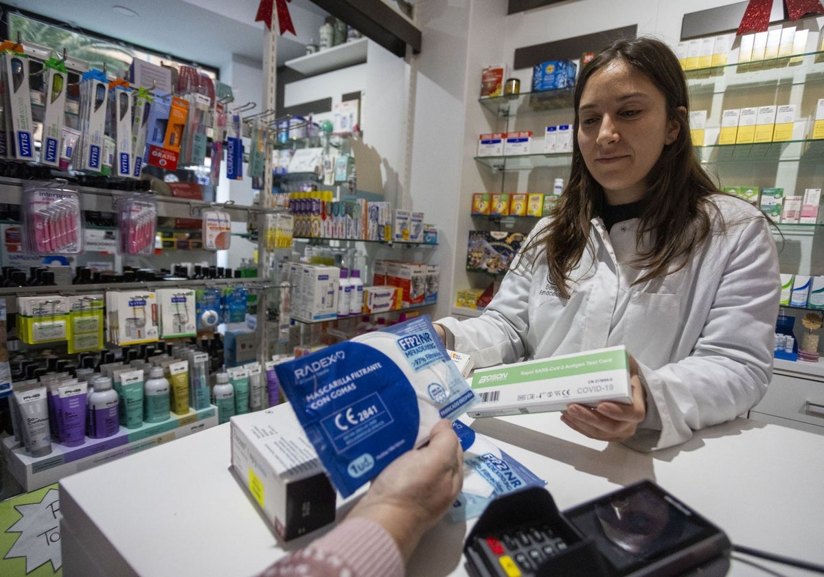 Una farmacéutica vendiendo mascarillas y test de gripe y covid a una clienta en Cáceres.