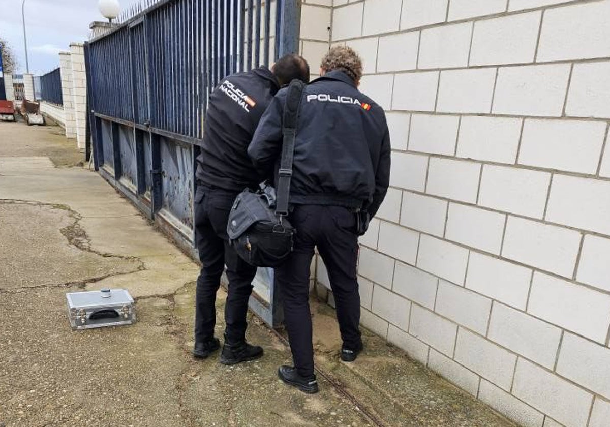 Dos policías nacionales toman huellas esta mañana en la entrada de la sede de Viñaoliva en Almendralejo.