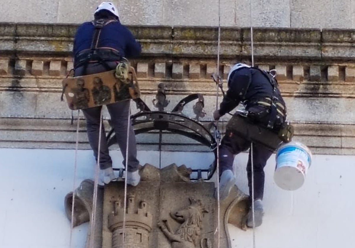 Los operarios trabajan sobre la fachada para retirar la corona del escudo.