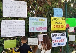 Dos alumnos del colegio Juan Vázquez colocan carteles en la verja del colegio Juan Vázquez.