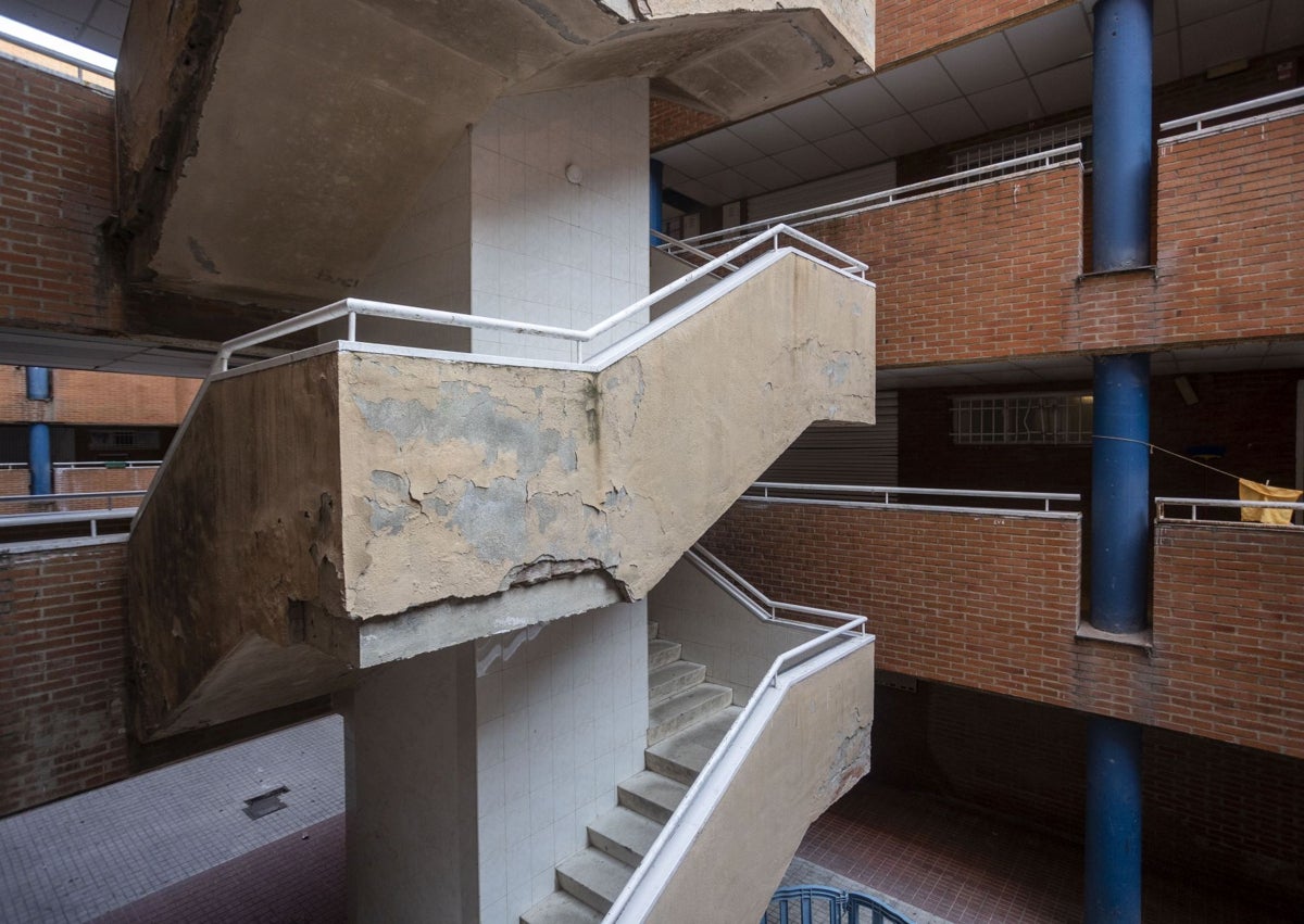 Imagen secundaria 1 - Agustina López señala las manchas de humedad en el techo. En otra imagen, las escaleras del bloque siguen sin mantenimiento. Debajo, vivienda tapiada tras haber sido okupada.