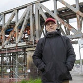 Ángel Caballero delante del Puente de Hierro, con los soportes sobre el suelo y el gato bajo las vías.