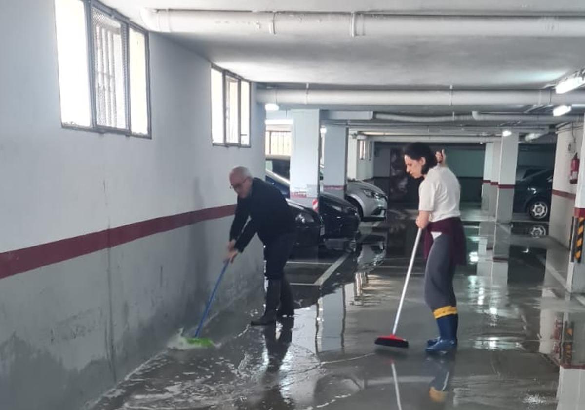 Los vecinos achicando agua en el garaje.