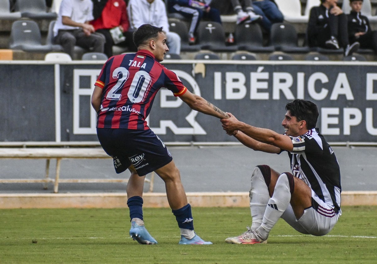 El azulgrana Tala ayuda a levantarse al blanquinegro Álex Herrera en el derbi de la primera vuelta.