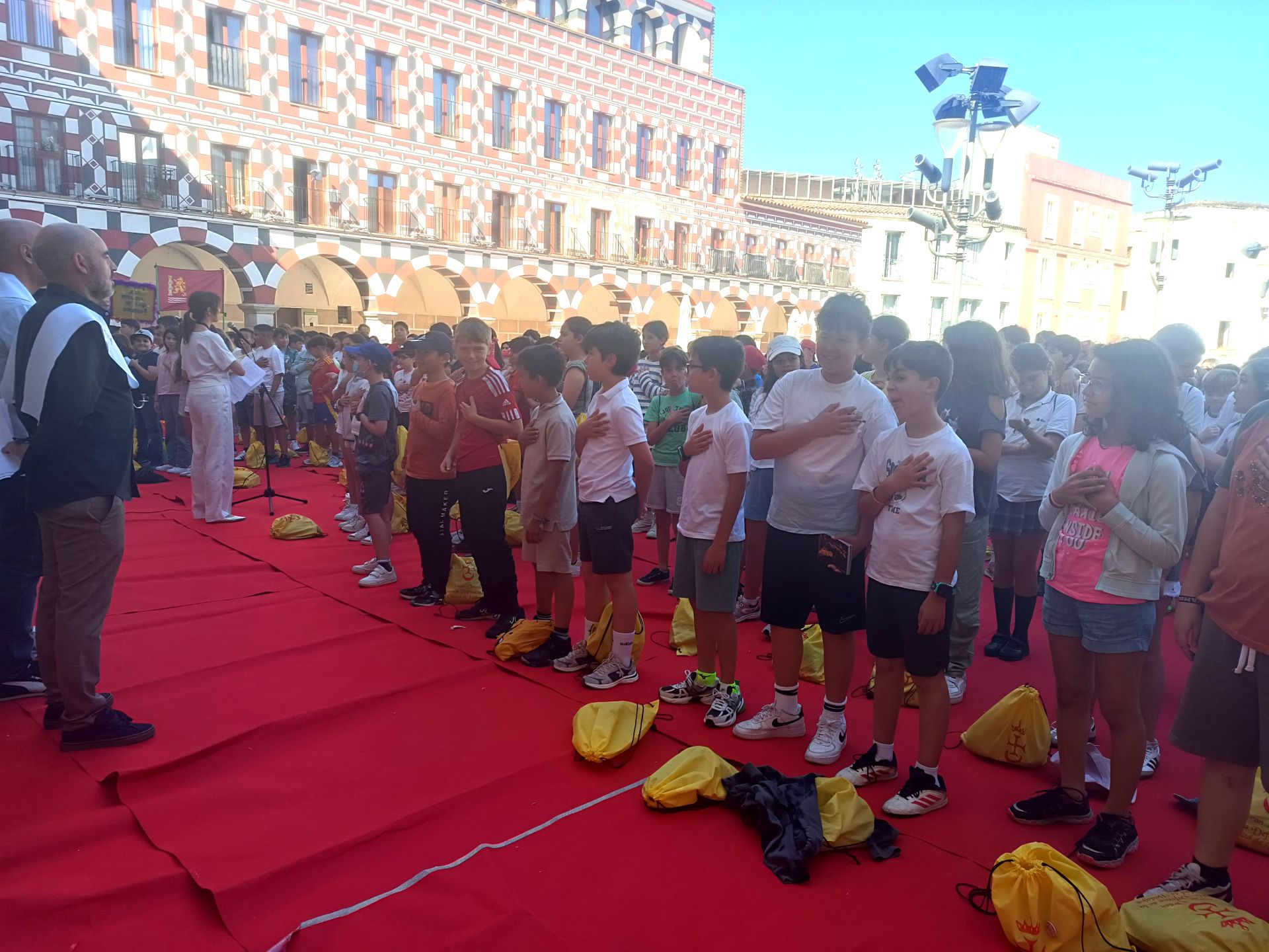 Los alumnos de los 12 colegios participantes escuchando el himno.