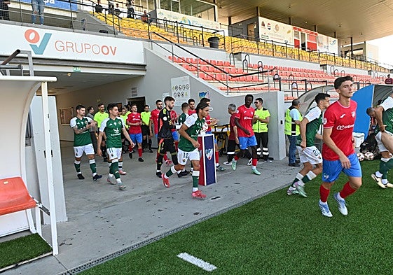 Los jugadores del Cacereño y Estepona saltan al terreno de juego este lunes en la reanudación del partido suspendido el día anterior.