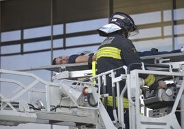 Un bombero ancla a la autoescala una camilla con una persona durante un simulacro de incendio en la torre Siglo XXI.