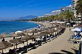 Playa con sombrillas y bañistas disfrutando del mar.