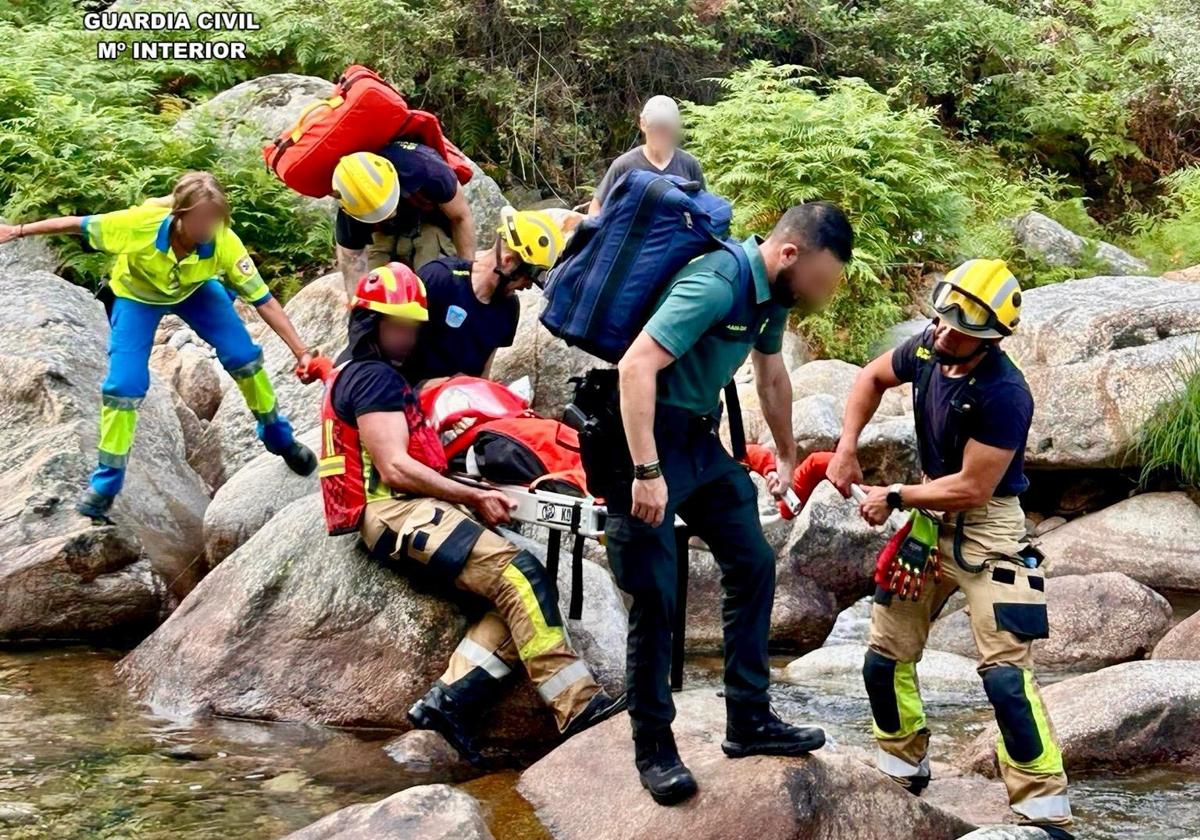 Bomberos y guardias civiles portan la camilla con la mujer accidentada el sábado en La Vera.