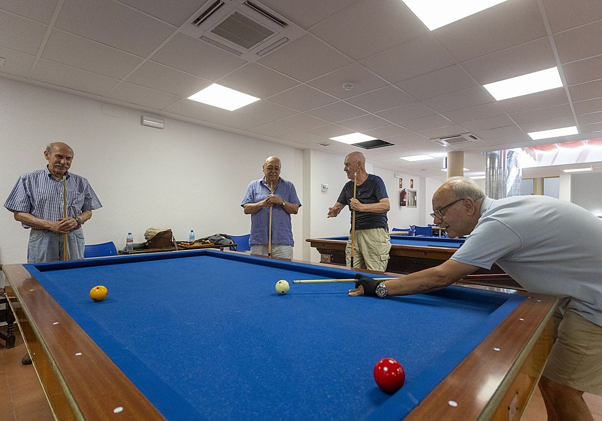 Usuarios del hogar de la Plaza Mayor de Cáceres juegan al billar en la segunda planta del edificio. En el techo, nuevas máquinas de aire acondicionado.
