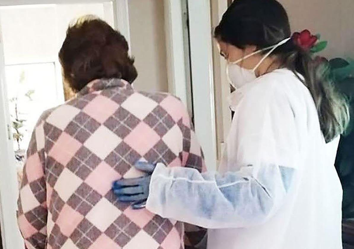 Imagen de archivo de una auxiliar de ayuda a domicilio ayudando a una persona mayor en su domicilio.